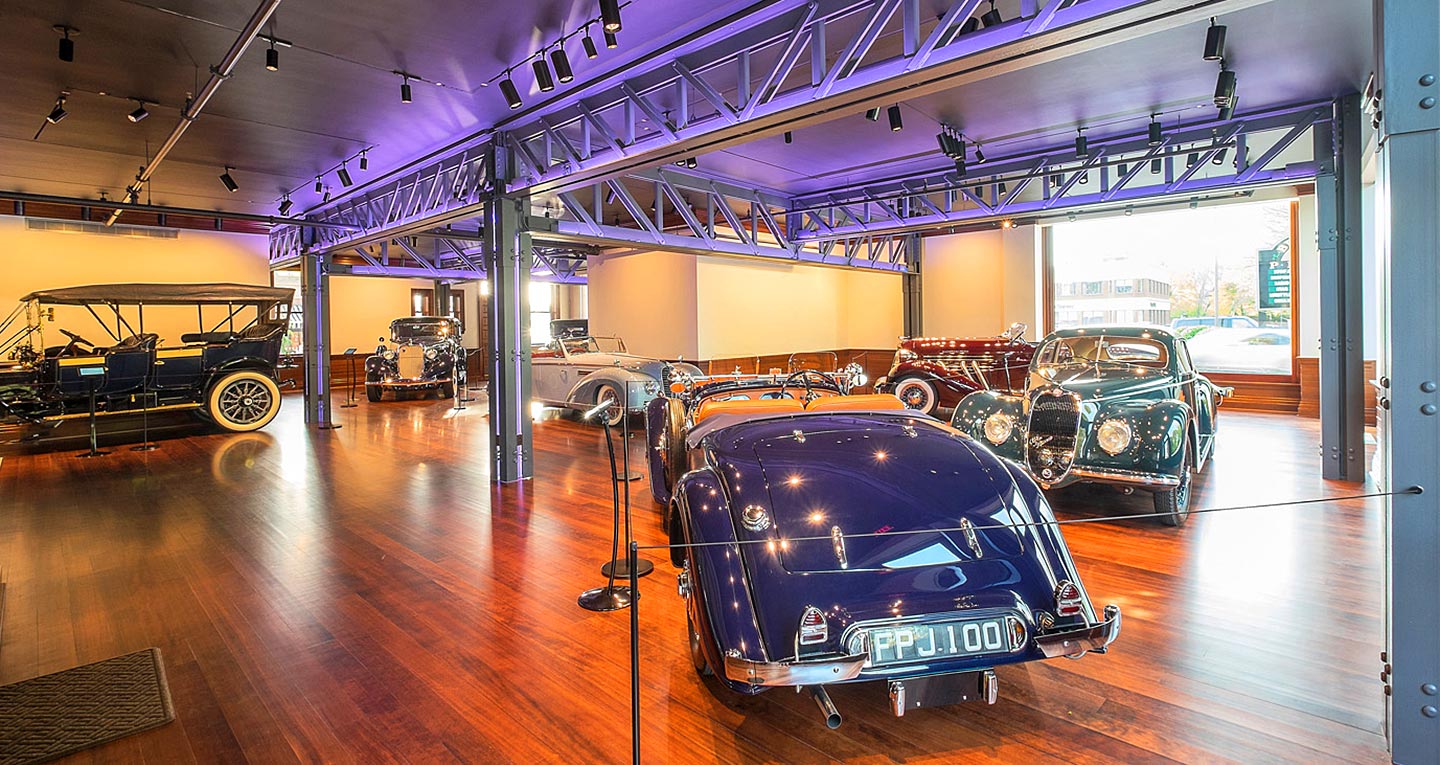 The interior of a car museum depicting 1920s, 30s, and 40s racers and luxury sedans
